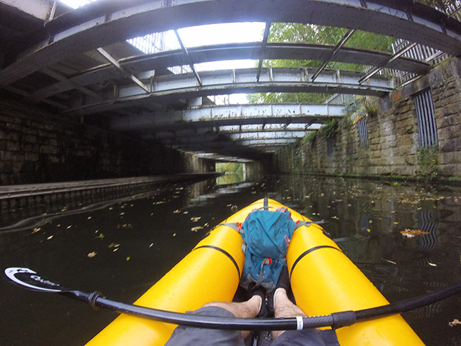 Packraft on canal under railway bridge.